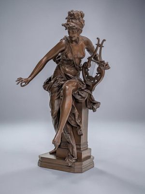 une statue en bronze représentant une femme assise sur un socle