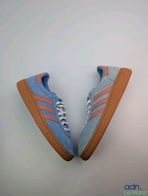 une paire de baskets Adidas bleues et orange sur fond blanc