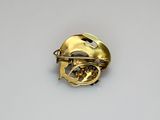 a close up of a gold broochle on a white surface