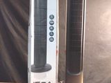 un ventilateur colonne noir posé à côté d'une boîte sur une table