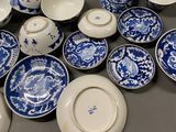 many blue and white plates and bowls sitting on a table