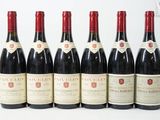six bouteilles de vin rouge alignées sur une surface blanche