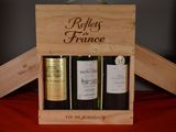 three bottles of wine in a wooden box on a table