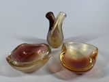 three small glass bowls and a small glass vase on a table