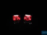 une paire de boucles d'oreilles rouges lumineuses posées sur une surface noire