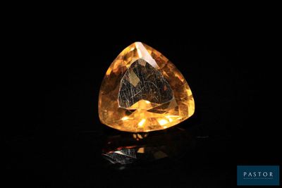 un diamant jaune sur une surface noire, avec un fond noir