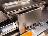 plan de travail en acier inoxydable dans une cuisine professionnelle, avec une spatule jaune posée dessus