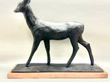statue of a deer standing on a wooden base against a white background
