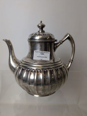 a silver tea pot sitting on a glass table