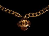a close up of a gold chain with a brown pendant