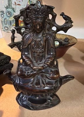 a statue of a woman sitting on a teapot
