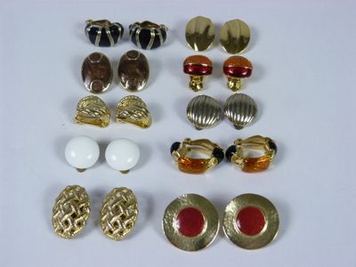 several pairs of gold and red earrings on a white surface