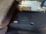 a dirty seat in the back of a car with a broken arm rest