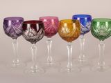 six verres à vin de couleurs différentes sont alignés sur une surface blanche