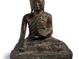 une image représentant une statue d'une personne assise sur un rocher