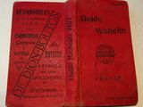 an old red book sitting on top of a table next to another book