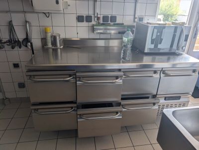 a stainless steel kitchen with a sink and a microwave on the counter