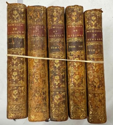 six vieux livres sont empilés sur une surface blanche