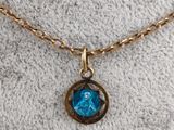 a gold necklace with a blue stone on a gold chain