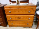 une commode en bois à trois tiroirs, surmontée d'un miroir