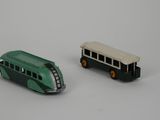 two toy buses sitting next to each other on a white surface