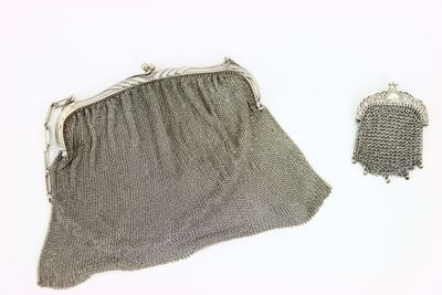 sac à main en maille argentée et pochette en cotte de mailles sur fond blanc
