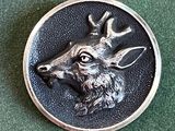 un gros plan d'un bouton en métal orné d'une tête de cerf