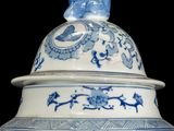 a large blue and white vase with a bird on top
