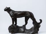 statue d'un chien noir debout sur une bûche, sur fond blanc