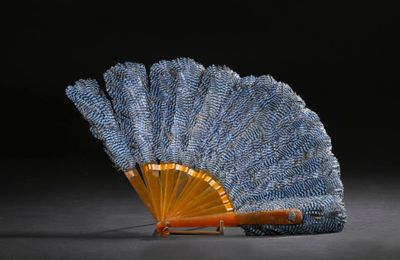 un éventail bleu et or posé sur une surface noire