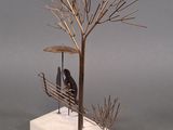 sculpture of a person sitting on a bench under a tree
