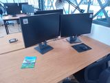 two computer monitors sitting on a desk in an office
