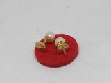 pair of pearl and gold stud earrings on a red felt surface