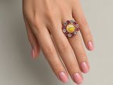 une image représentant la main d'une femme avec une manucure rose et une bague jaune et blanche