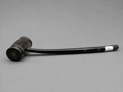 une vieille pipe posée sur une table, devant un fond gris