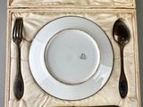 a place setting with a plate, spoon, and spoon rest