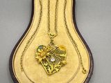 an image of a gold necklace in a case with a bird on it