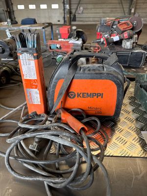 an orange and black welding machine sitting on top of a table next to other tools