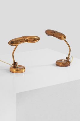 two gold desk lamps on a white surface with a white background
