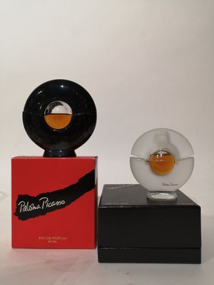 un petit objet en verre posé sur un socle noir, à côté d'une boîte rouge