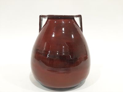 a brown vase with a handle on a white surface