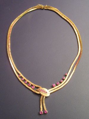 a close up of a gold necklace with pink stones on it