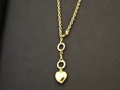 un collier en or auquel est suspendu un pendentif en forme de cœur