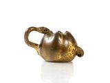 a gold teapot on a white surface with a white background
