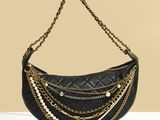 un sac à main noir orné de chaînes dorées et de perles qui y sont suspendues