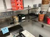 stainless steel shelves in a commercial kitchen with utensils and a microwave