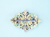 a gold brooch with a blue and green design on it