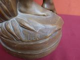 une statue représentant une femme assise sur un pot