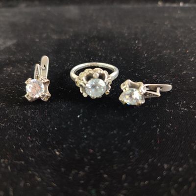 a close up of three rings and a pair of earrings on a black surface