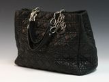 une image représentant un sac à main noir posé sur une surface blanche